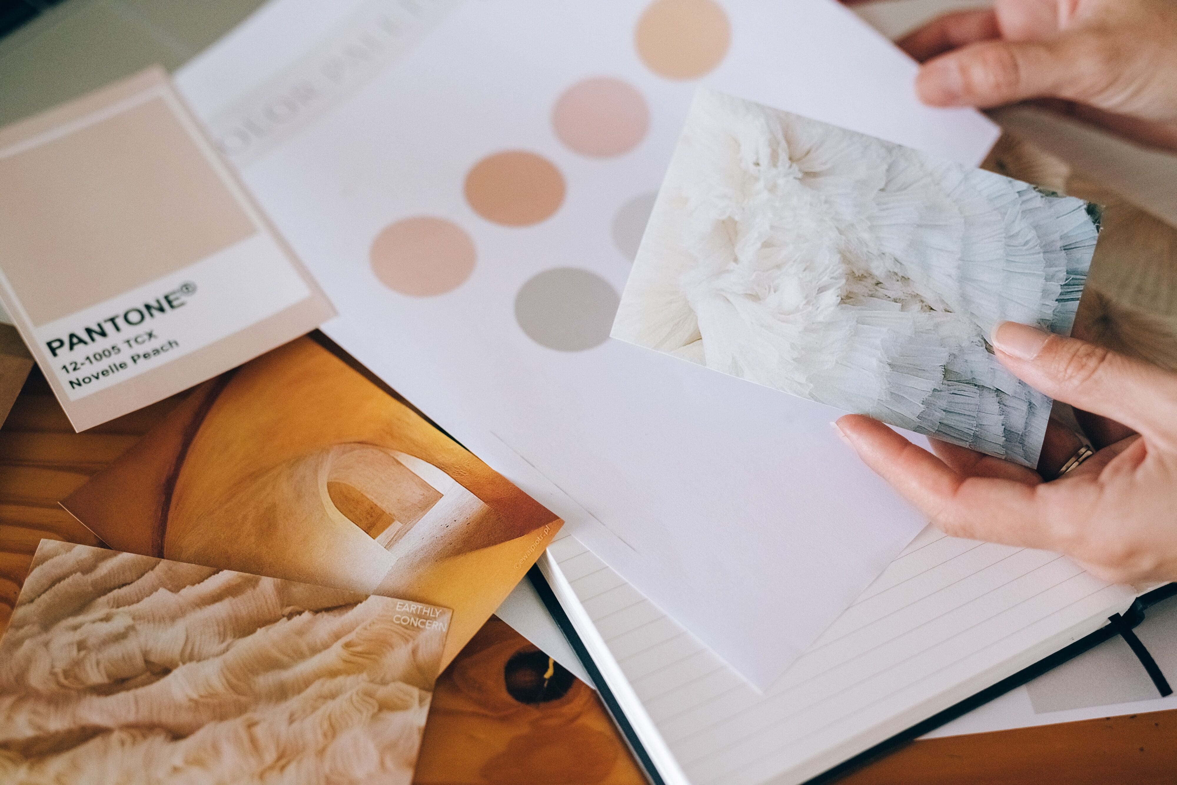 close-up of someone comparing marketing materials to a pale color palette that color psychology says provides both a sense of simplicity and warmth